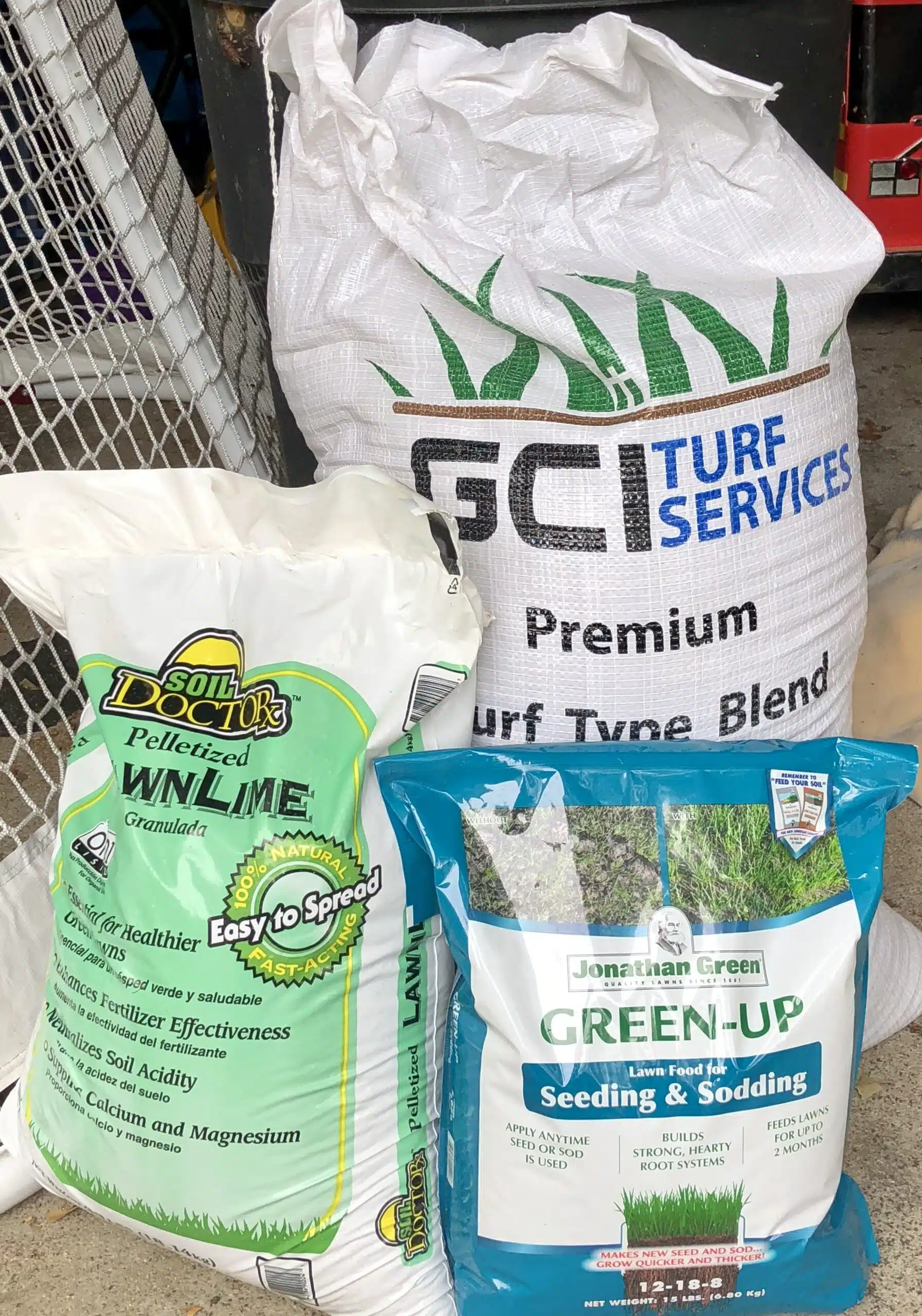Bag of GCI turf-type tall fescue grass seed next to Jonathan Green starter fertilizer with lime