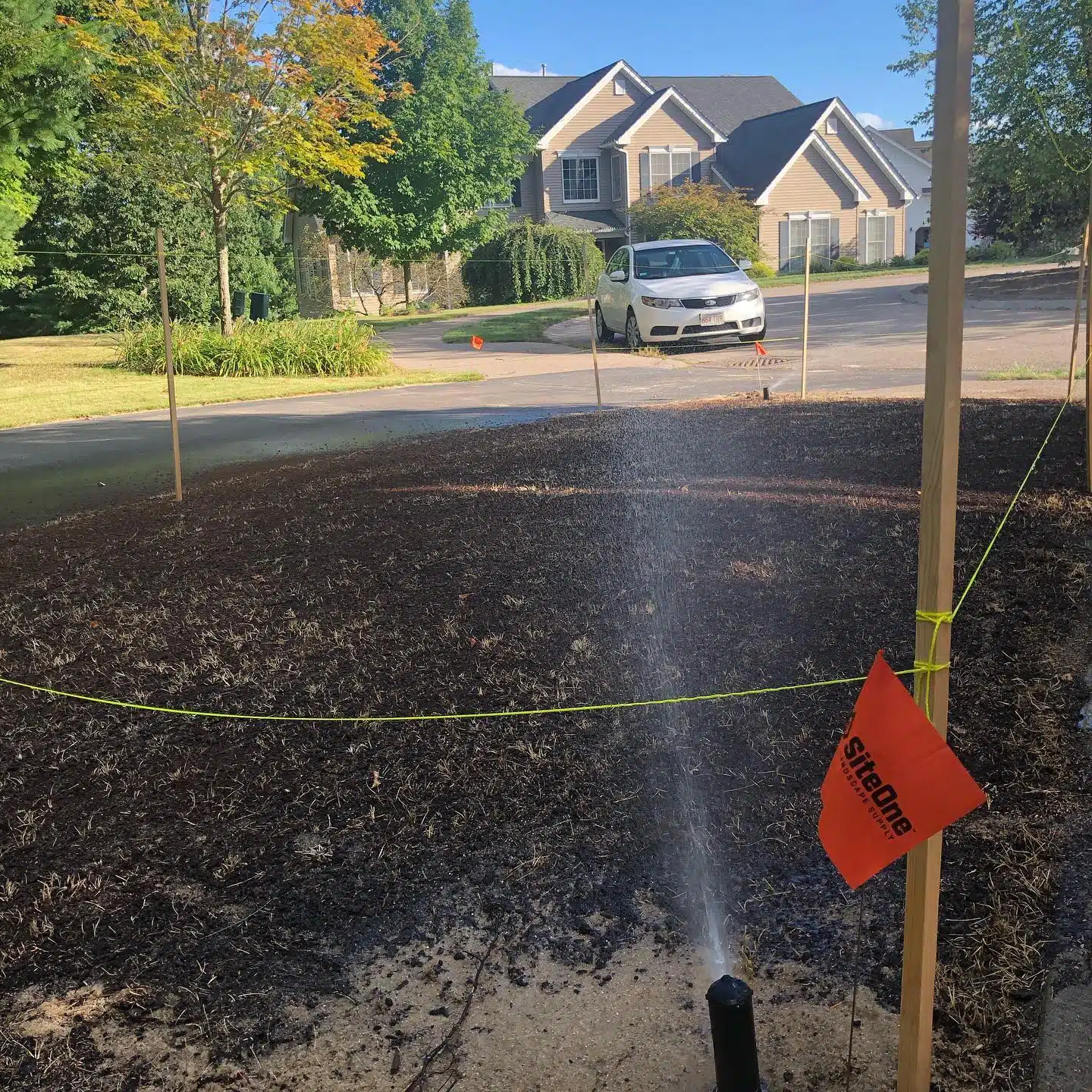 Watering newly spread grass seed on bare soil
